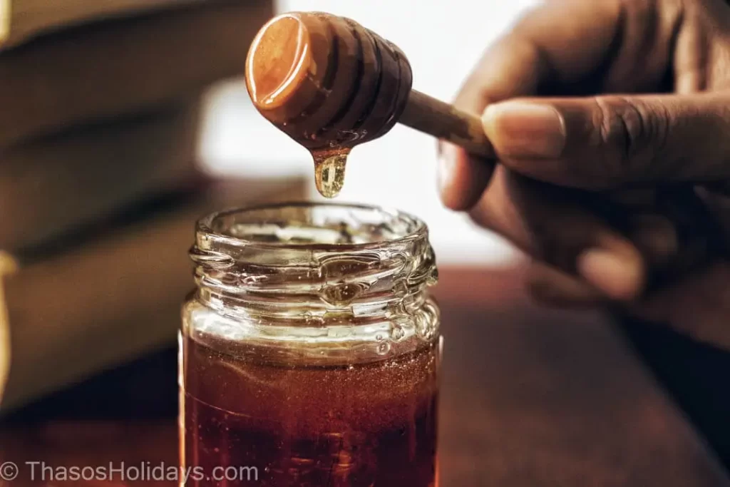 Hand taking some honey from a bowl