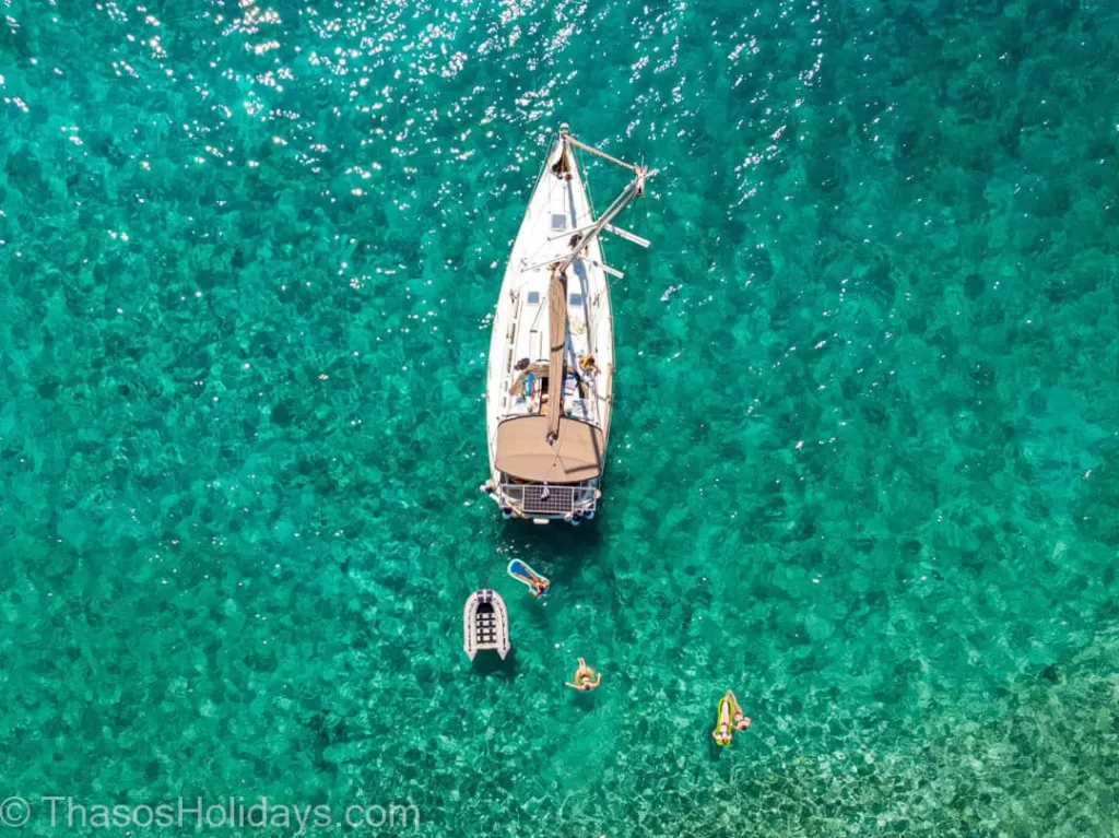 Yaghting in emerald waters with people on top sunbathing and having fun